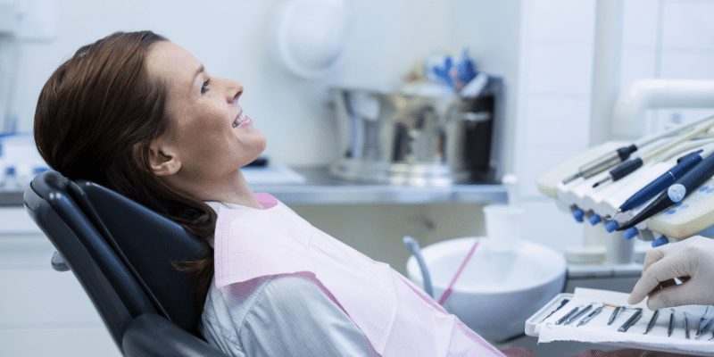Women sitting in dental chair speaking to dentist - All About Dental Bibs and Why They Are Essential for More than Dentists