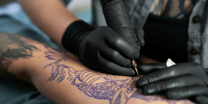Tattoo artist starting to work on an arm - Prioritizing Safety in Tattooing: Why You Need Medical-Grade Sanitizers